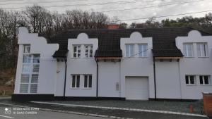 una casa blanca con techo negro en Szikla Vendégház Sopron en Sopron