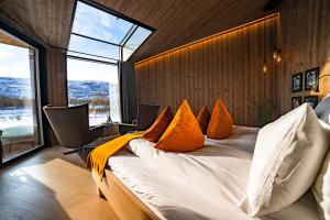 1 dormitorio con 1 cama grande con almohadas de color naranja en Sorrisniva Arctic Wilderness Lodge, en Alta