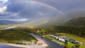 a rainbow in the sky over a river at Sorrisniva Arctic Wilderness Lodge in Alta