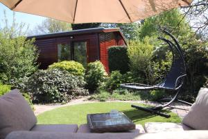 a garden with a chair and an umbrella at Veluwe Park Reewold Chalet Infinity in Putten