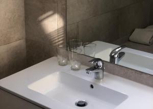 een wastafel in de badkamer met 2 glazen en een spiegel bij Giorgio in Antwerpen