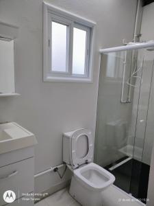 uma casa de banho branca com um WC e um chuveiro em FRANCIS HOTEL MAR em Caraguatatuba