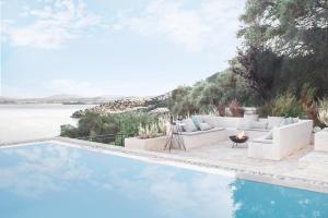 een zwembad met banken en een open haard naast het water bij Korypho Villas in Barbati