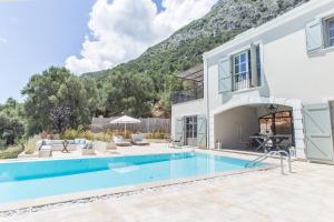 een huis met een zwembad voor een berg bij Korypho Villas in Barbati