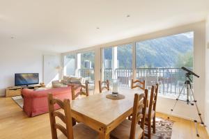 a living room with a table and chairs and a large window at Résidence La Vallée Blanche - Happy Rentals in Chamonix-Mont-Blanc
