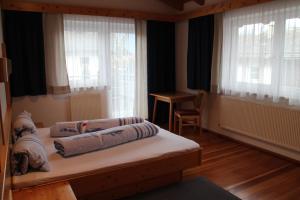 a bedroom with two beds and a table and windows at Appart Gabl in Arzl im Pitztal