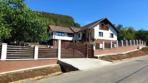 a house with a fence next to a street at Vatra Strabunilor in Moigrad