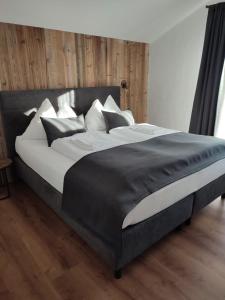 een groot bed met zwart-witte lakens en kussens bij Bergidyll 12 by Alpenidyll Apartments in Ramsau am Dachstein