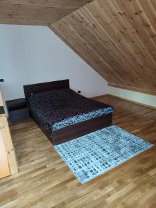 een kamer met een bed en een houten vloer bij Apartamentai Pušyne in Druskininkai