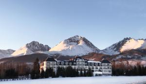a building in front of a mountain with snow at Vila Horec - depandance hotela Hubert Vital Resort in Svätý Jur