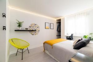 um quarto com uma cama e uma cadeira amarela em Apartamento inteligente con vistas a la Alhambra em Granada
