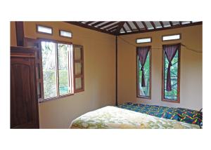 a bedroom with a bed and two windows at Sanggar Pantcha Indra in Kemuning