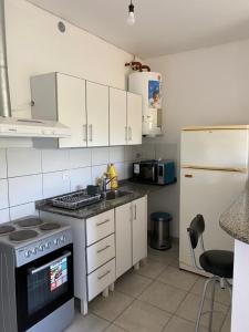 a kitchen with white cabinets and a stove and a refrigerator at Departamento Temporario La Quebrada in La Rioja