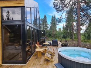 une maison en verre avec un bain à remous sur une terrasse dans l'établissement Ekornredet (The Squirrel Nest), à Kongsberg