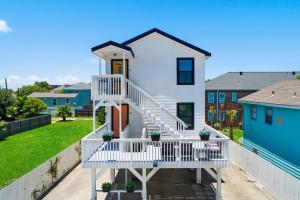 a white house with a white staircase in a yard at Soleil House - Unit D in Galveston