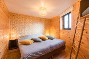 Schlafzimmer mit Holzwänden und einem Bett mit Kissen in der Unterkunft Le Scandin'Havre in Hannut