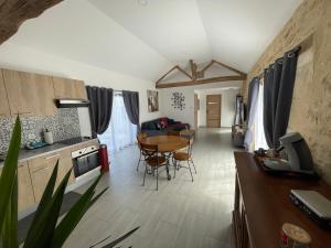 a kitchen and living room with a table and chairs at Longère Linaroise & SPA à 15 min du Futuroscope 