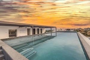 a swimming pool on top of a building with a sunset at Endless Summer - 2Bed 2Bath Condo - Seasonly Heated Pool with Ocean Views - 5min walk to Beach - Fibre Internet - Sleeps 6 in Cabo San Lucas
