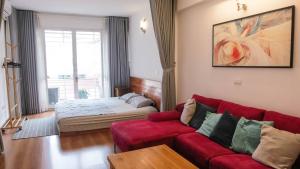 河內的住宿－Wind Chimes Hideaway - Apartment In Central Hanoi，客厅配有红色的沙发和床。