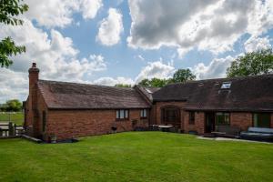 una casa in mattoni con un grande prato di fronte di Coach House at Oaks Barn Farm Alcester with optional hire Salt water hot tub 