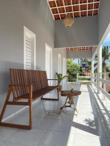 a porch with a wooden bench and a table at Mar de Gente Pousada in Praia de Moitas