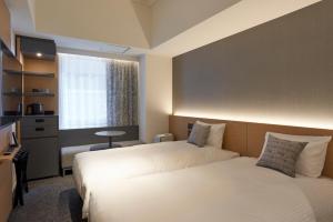 Cette chambre comprend deux lits et une télévision. dans l'établissement CROSS Life Hakata Yanagibashi, à Fukuoka