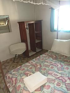 una camera con un grande letto e una sedia di Hotel restaurant Foulpointe Loisir a Foulpointe