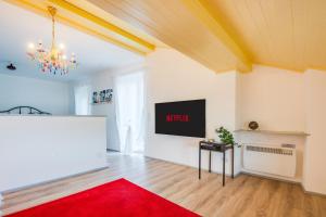 ein Wohnzimmer mit einem TV und einem roten Teppich in der Unterkunft Vista lago Splendida casa a 5 stelle - Lugano Collina in Aldesago