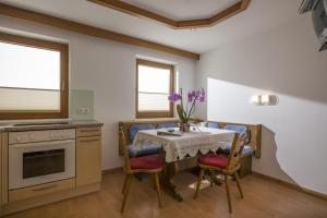 a dining room with a table and chairs and a kitchen at Ferienwohnung Unterperler in Hippach