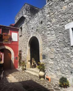 un bâtiment en pierre avec un chien assis dans la porte dans l'établissement PietraViva Casa vacanze FAICCHIO, NON VISANTI, à Visanti