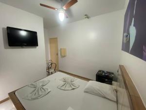 um quarto com uma cama e uma televisão na parede em Hotel Bom Gosto em Salvador