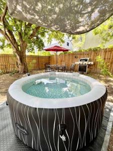 a hot tub in a backyard with an umbrella at Belair Lux 3BR 3BA Home W Private Hot tub, 3k Arcade Games & private garage- 5mins to the Airport in San Antonio