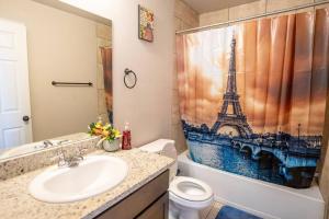 ein Badezimmer mit einem Waschbecken und einem Duschvorhang mit dem Eiffelturm in der Unterkunft Belair Lux 3BR 3BA Home W Private Hot tub, 3k Arcade Games & private garage- 5mins to the Airport in San Antonio