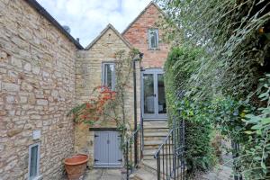 una antigua casa de piedra con una puerta y escaleras en Ostlers Loft en Chipping Campden