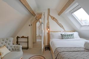 a bedroom with a bed and a chair in a attic at Ostlers Loft in Chipping Campden