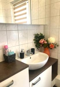 a bathroom with a sink and a mirror and flowers at Apartment Enno in Auerbach