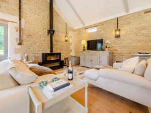 a living room with two white couches and a fireplace at The Barn in Shipton under Wychwood