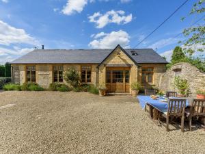 a stone house with a table and chairs in front of it at The Barn in Shipton under Wychwood