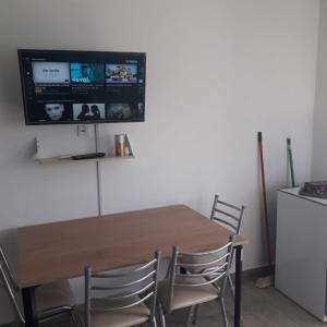 uma mesa de jantar com cadeiras e uma televisão na parede em Alquilerpordiaviedma em Viedma