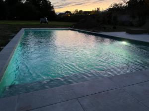 a swimming pool in a backyard at sunset at Chambres d'Aumont in Aumont