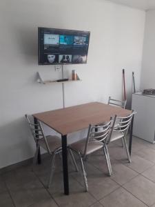 mesa de madera con sillas y TV en la pared en Alquilerpordiaviedma en Viedma