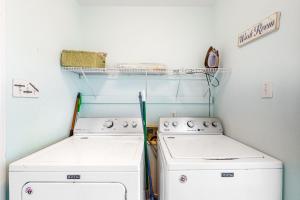 a laundry room with two washing machines and a shelf at Sunset Beach in Dauphin Island