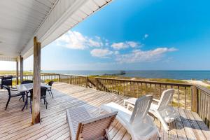 a deck with a table and chairs and the ocean at Sunset Beach in Dauphin Island