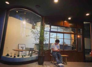 un hombre sentado en una mesa frente a un edificio en -WiFi強- 那須の入り口JR黒磯駅から歩いて7分の宿泊ビル 完全プライベートフロア en Kuroiso
