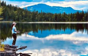 a woman standing in a lake holding a fishing rod at Åreskutans Fjällstuga in Huså +27 photos