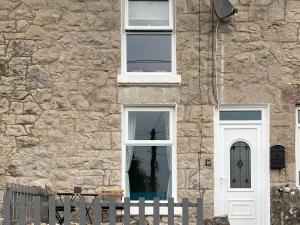 a building with a white door and a fence at Quarrymans in Llysfaen