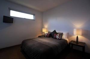 a bedroom with a bed with two lamps and a window at Battery Cove Beach Front Apartment in Port Fairy