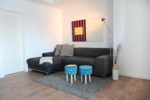 ein Wohnzimmer mit einem schwarzen Sofa und einem blauen Stuhl in der Unterkunft Ferienwohnungen im HOF68 in Münster