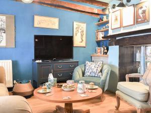 a living room with a table and a tv at Teal Cottage in Honiton
