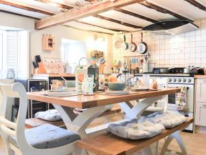 a kitchen with a wooden table with chairs around it at Teal Cottage in Honiton